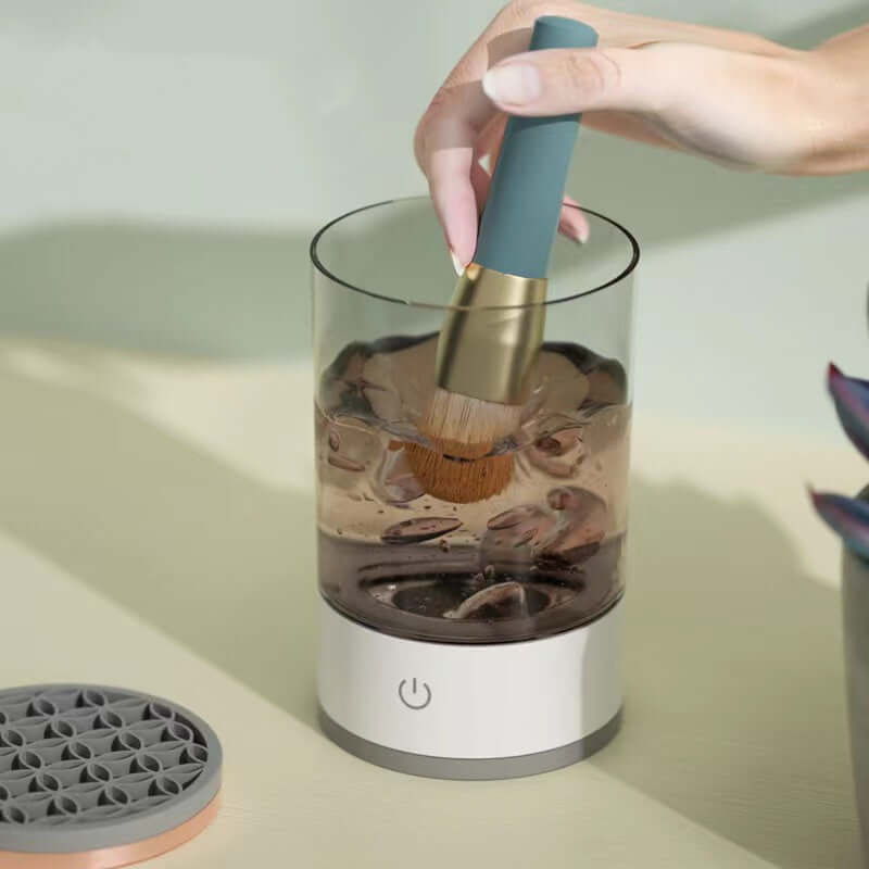 USB Automatic Eye Shadow Brush Cleaner in use with makeup brushes submerged in cleaning solution.