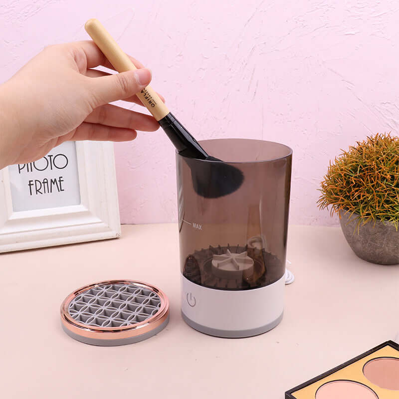 USB Automatic Eye Shadow Brush Cleaner in use with makeup brushes submerged in cleaning solution.